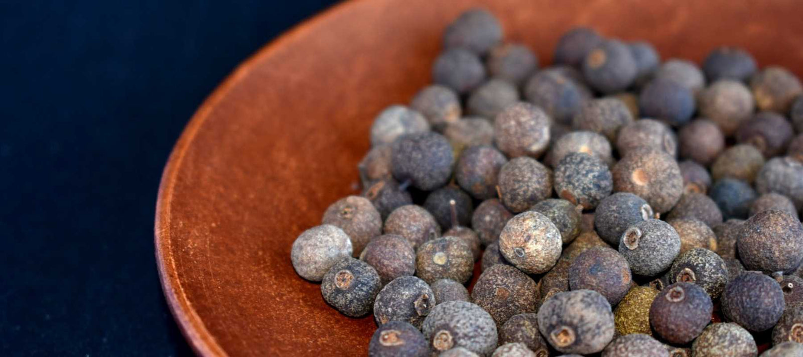 Ein Häufchen Kubebenpfeffer vor schwarzem Hintergrund