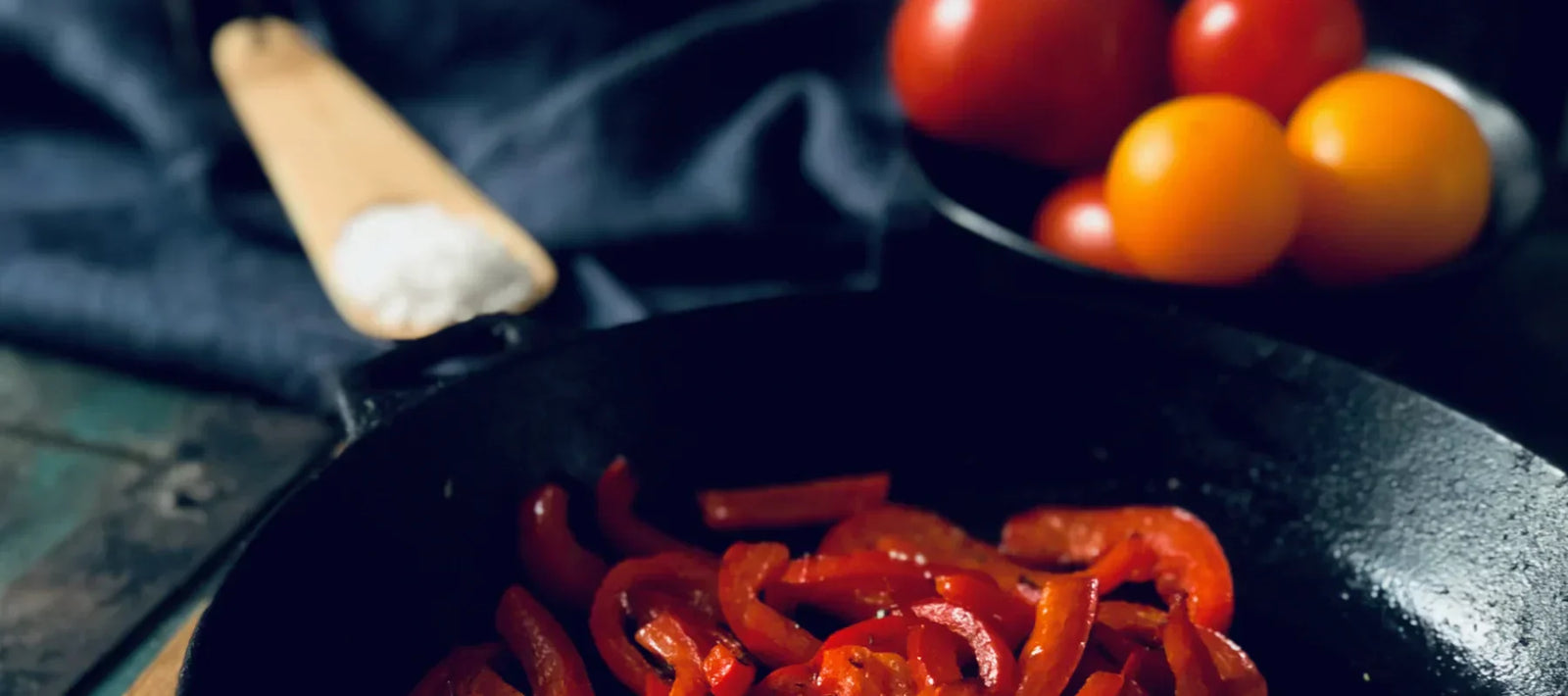 mediterrane Ernährung, rote Paprika in einer Pfanne mit Meersalz und einer Schale Tomaten