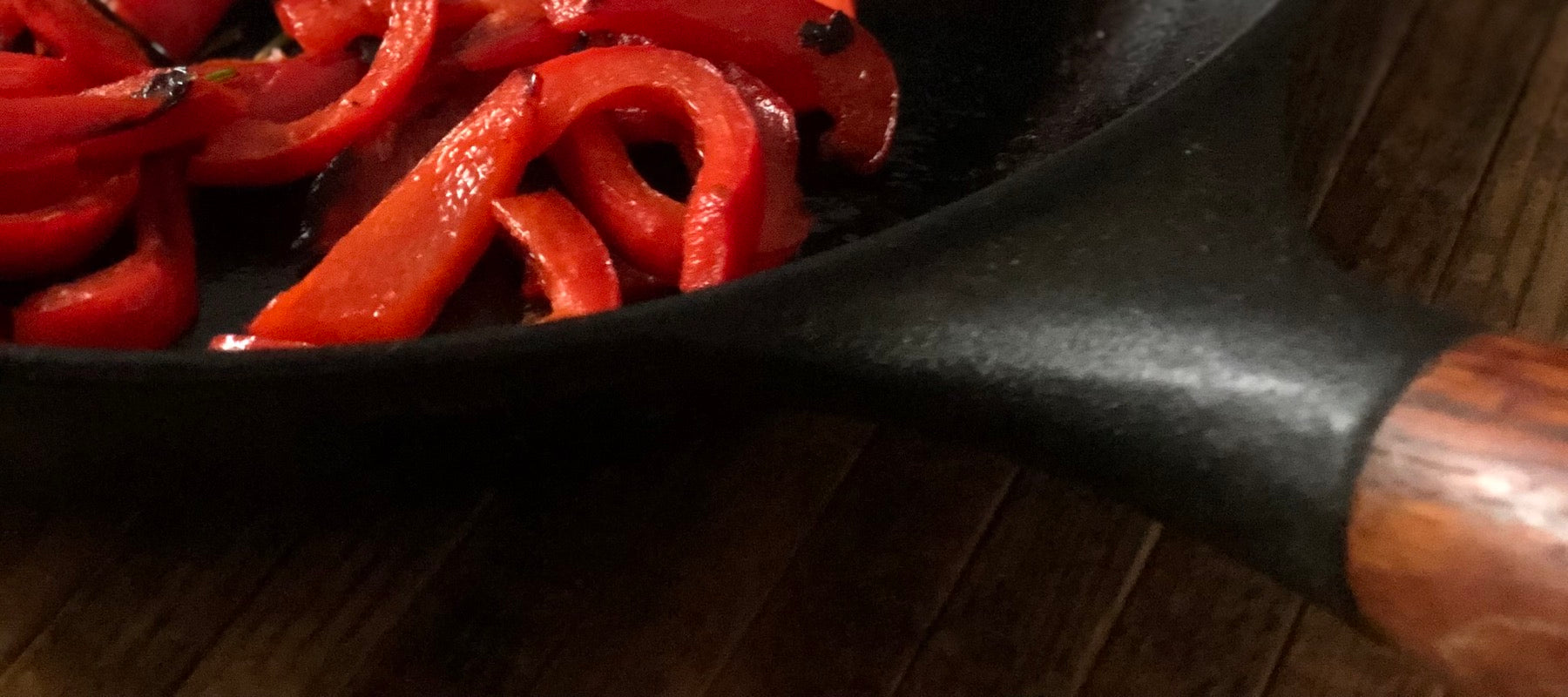 Rote Paprika mit Olivenöl erhitzt in schwarzer Pfanne